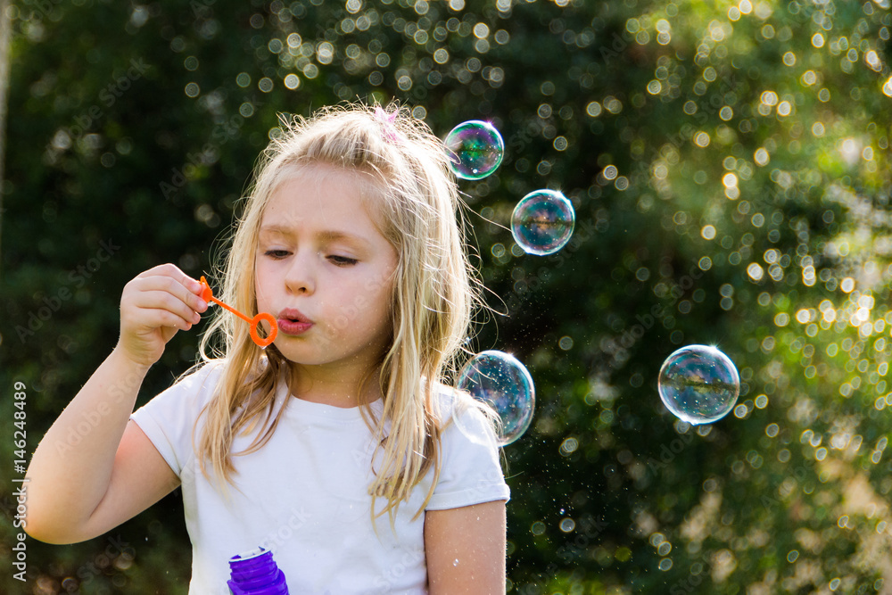 adorable school age girl blowing bubbles outside