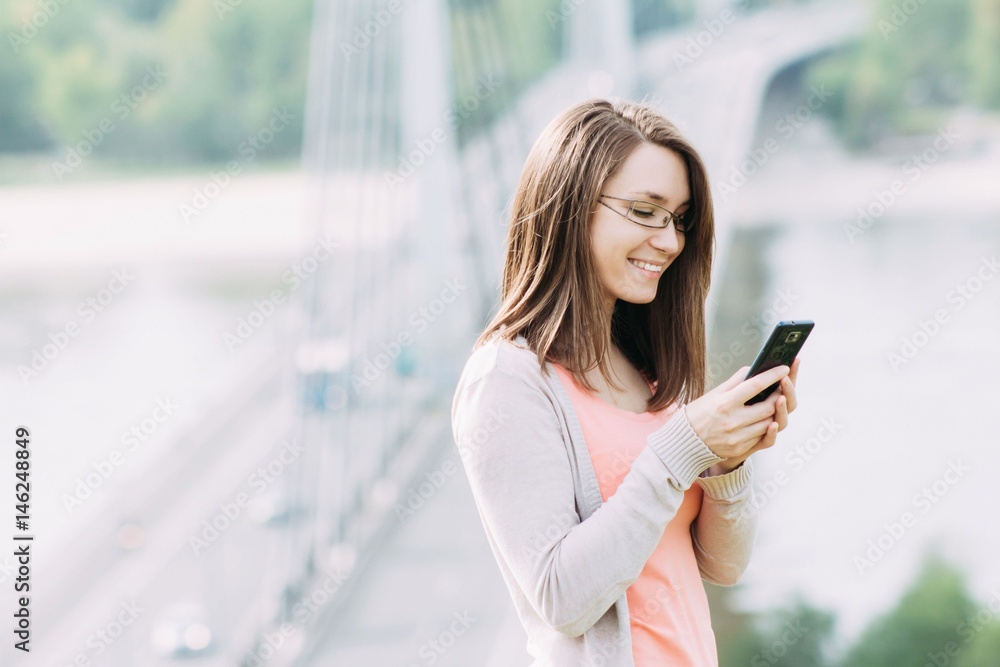 Fototapeta premium Young woman using smartphone outdoor
