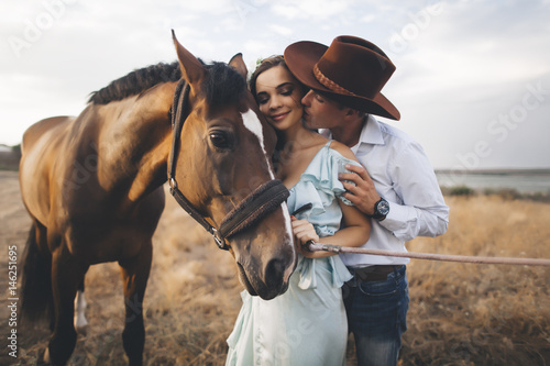 Caucasian cowboy kissing woman on cheek near horse photo