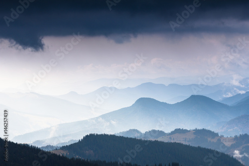 Landscape of mountains in spring. View of green forest and misty hills.
