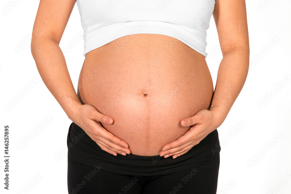 Pregnant woman embracing her bare belly with white background Pregnant woman embracing her bare belly with white background