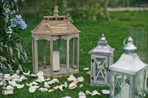 Fancy lanterns with white candles stand on green lawn