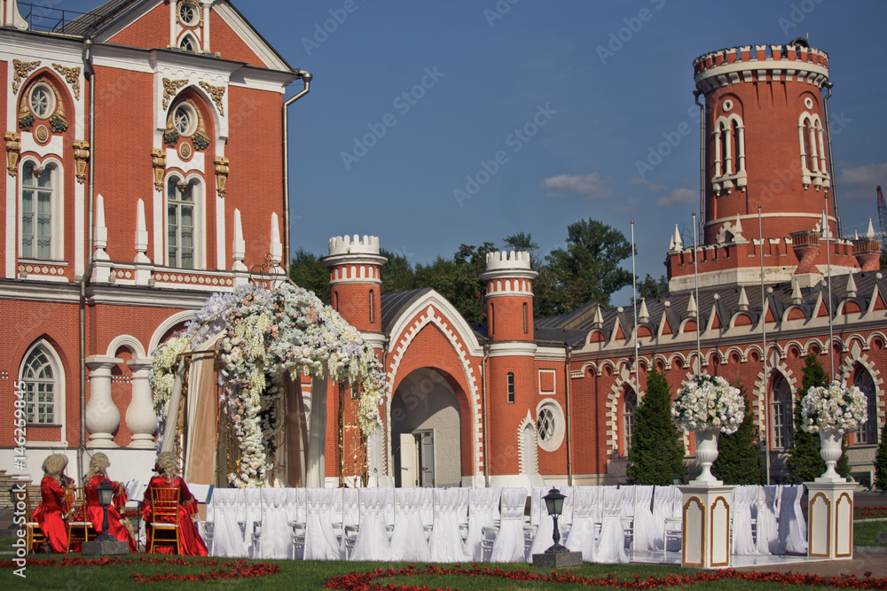 Obraz premium Beautiful wedding altar made of brown and white cloth and rich garlands of flowers stands before red house