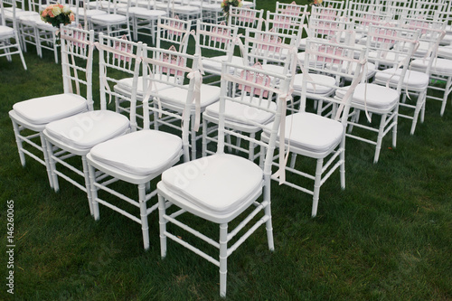 White chairs stand in the row on green lawn