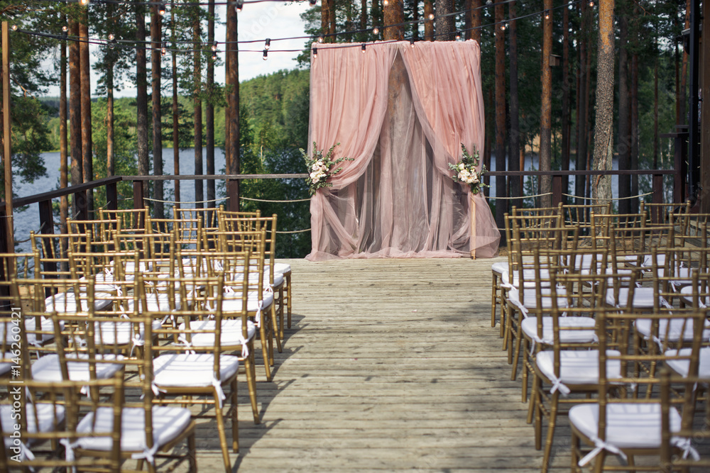 Golden chairs stand in the rows before pink wedding altar Golden chairs stand in the rows before pink wedding altar