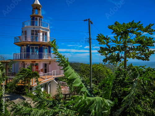 Roatan, Honduras Lighthouse building. Landscape of the island with a blue sky and green vegetation in the background. photo