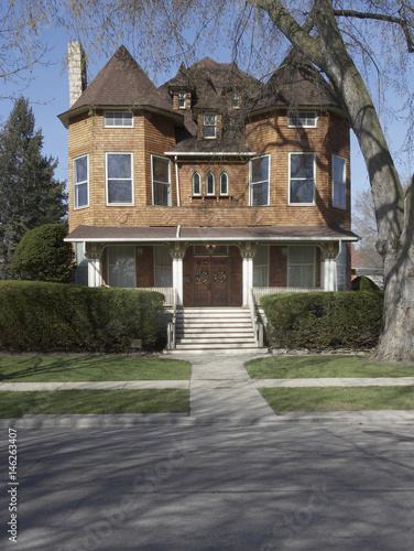 Cedar shake three story home, with gothic windows, and three small dormers, porch with carved fretwork, photo