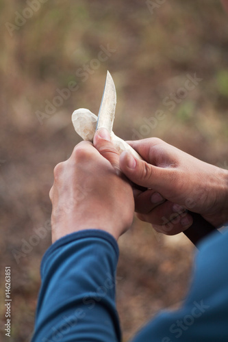 Man's hands working suit carving a wooden spoon with a knife photo