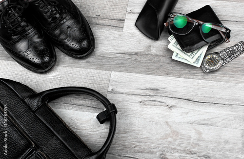 Man accessories in business style. Briefcase, brogues , shoes,wallet with money and other luxury businessman attributes on leather black background, fashion industry, top view.Copy space