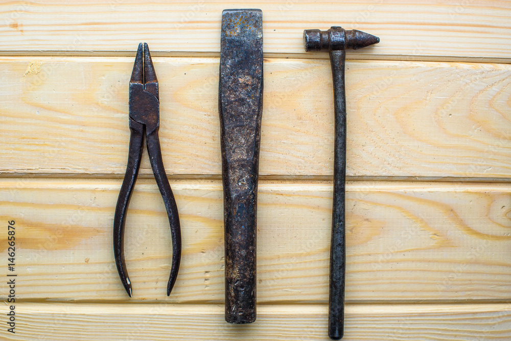 Old rusty pliers old hammer on wood background. Old rusty industrial home tools Old rusty pliers old hammer on wood background. Old rusty industrial home tools