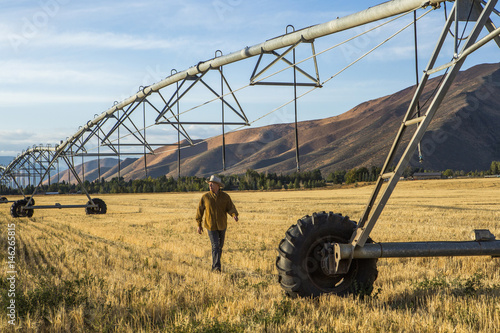 Caucasian farmer walking near irrigation equipment photo