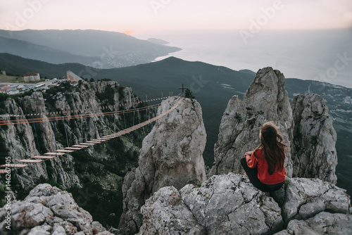 Caucasian woman sitting on mountain near footbridge