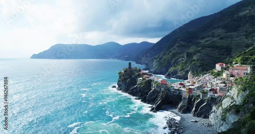 aerial view of travel landmark destination Vernazza, a small mediterranean sea town, Cinque terre National Park, Liguria, Italy. Afternoon sunny and cloud weather. 4k aerial drone side video shot