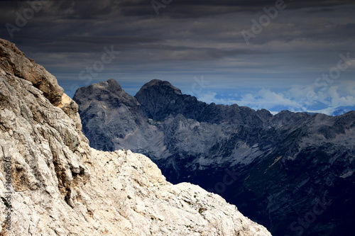 Jalovec and Mangart peaks and Mojstrovke ridge from rocky slopes of Kanjavec, Julian Alps, Triglav National Park, Slovenia, Europe, in the background Austria in clouds