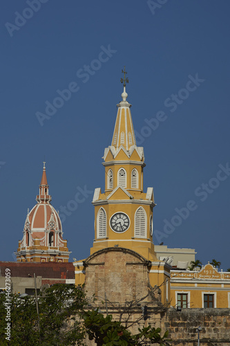 Historic Clock Tower (Torre del Reloj) above the main gateway into the historic walled city of Cateragena de Indias in Colombia. Tower of the historic Cathedral of Saint Catherine of Alexandria beyond photo