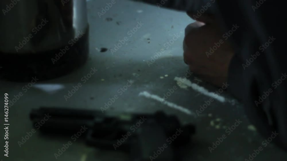 Cocaine drug dealer aligns line and snorts coke near gun in drug lab Cocaine drug dealer aligns line and snorts coke near gun in drug lab