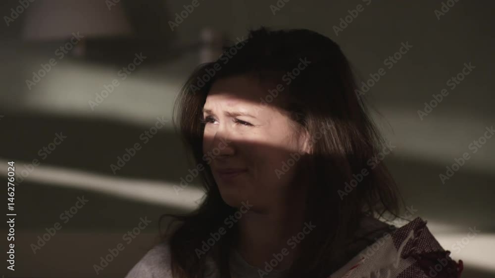 Young cute sleepy caucasian brunette girl sits on bed caress hair and finger point at camera. Beam of light falls on her face in early morning, close up slow motion, warm tone Young cute sleepy caucasian brunette girl sits on bed caress hair and finger point at camera. Beam of light falls on her face in early morning, close up slow motion, warm tone