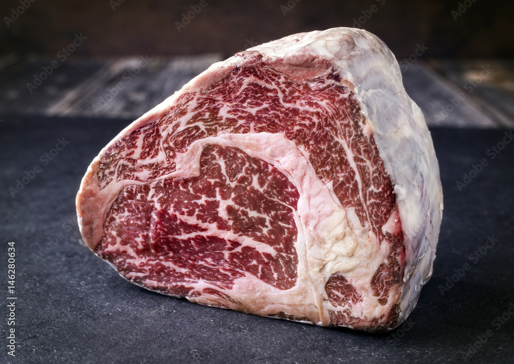 Rohes gereiftes Black Angus Entrecote Steak als close-up auf einer Schieferplatte