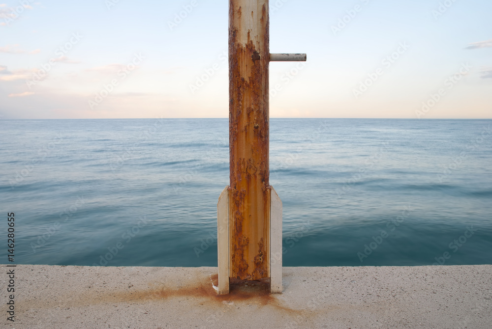 rusty flag pole at the sea edge