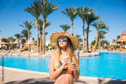 Portrait of a smiling young woman holding a cocktail while on summer vacation