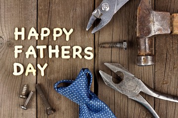 Happy Fathers Day wood letter greeting with tools and tie on a wooden background