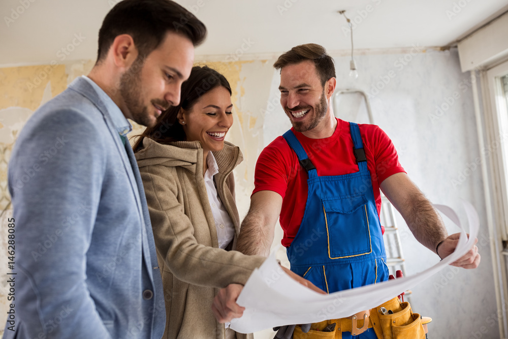 Beutiful young couple looking blueprints of their home with handyman Beutiful young couple looking blueprints of their home with handyman