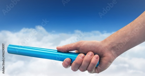 Hand with blue baton against clouds and blue sky