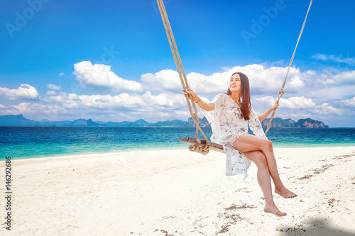 Beautiful woman sitting on a swing on the beach in Krabi, Thailand
