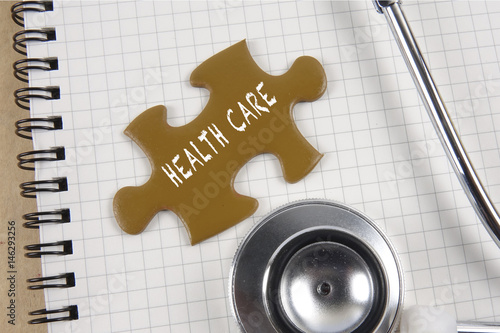 Medical concept with stethoscope,piece of puzzle and coins with HEALTH CARE conceptual text. photo