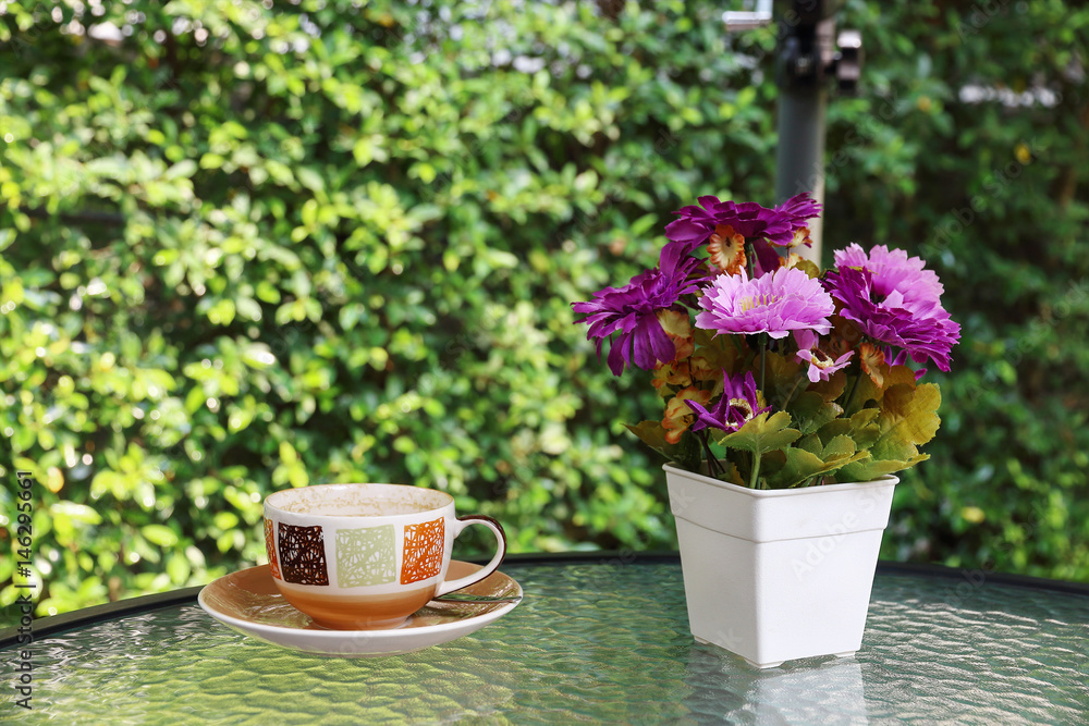 flower vase and coffee cup on glass table with blur green background flower vase and coffee cup on glass table with blur green background