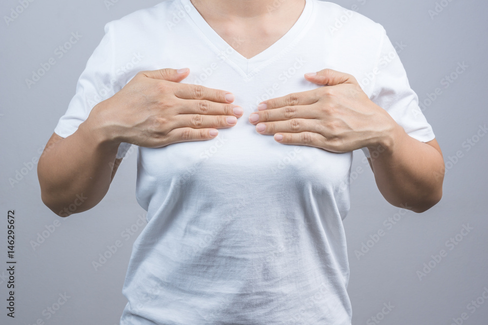 Woman putting her hand on breast for checking size or cancer awareness Woman putting her hand on breast for checking size or cancer awareness