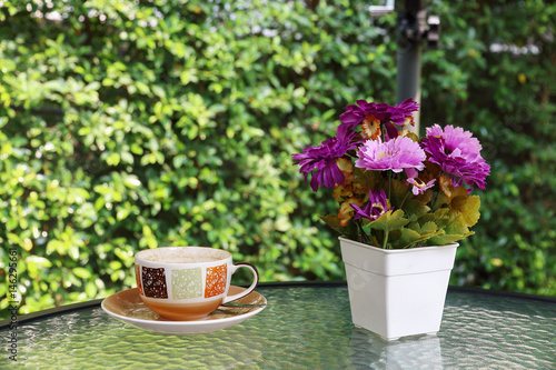Fototapeta Naklejka Na Ścianę i Meble -  flower vase and coffee cup on glass table with blur green background