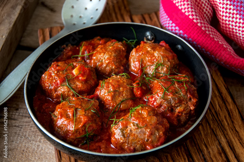 Homemade roasted beef meatballs with sour tomato sauce. Close up and rustic style.