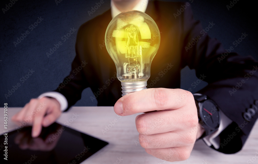 man in suit holding a glowing yellow light bulb man in suit holding a glowing yellow light bulb