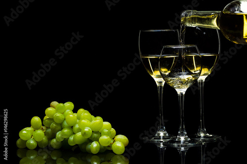 Glasses for wine and a bunch of grapes on a black background