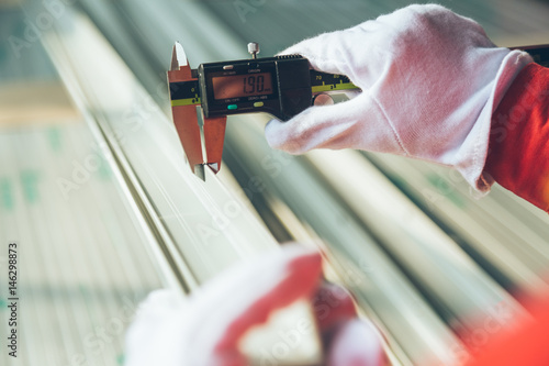 worker measuring aluminum product with vernier caliper in a plant. photo