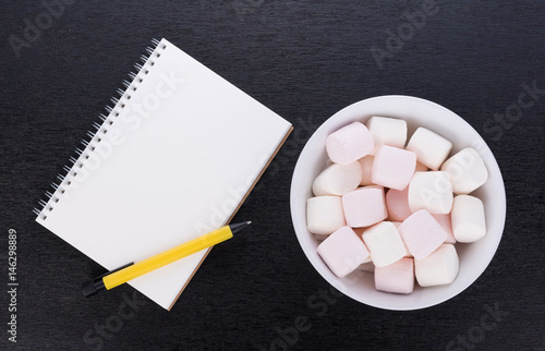 Marshmallows in a bowl on black wooden background