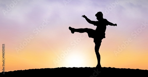 Silhouette man exercising against sky during sunset