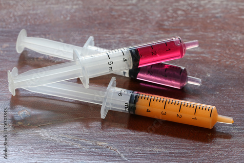 Syringe with colorful kids medicine syrup on wood