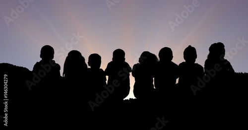 Silhouette children sitting against sky