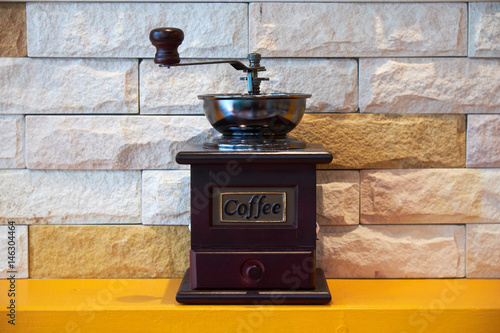 Classic manual coffee grinder machine on orange wooden table. retro style.