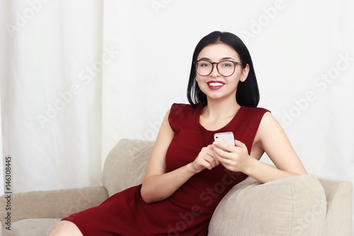 Young charming female freelancer chatting on mobile phone while sitting on the couch photo