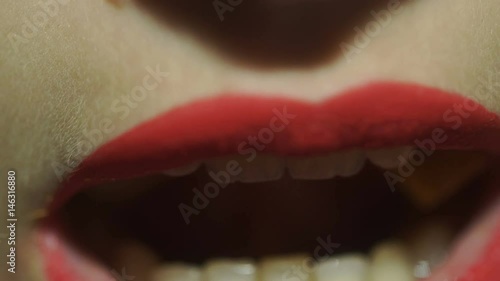 close up of young girl with red lips eats potate chips photo