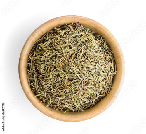 Dried rosemary leaves in wooden bowl over white background