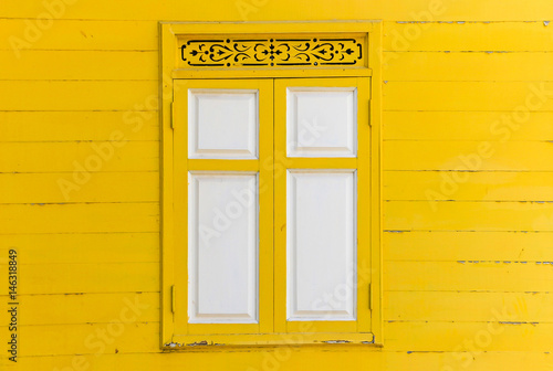 yellow wooden wall with white window