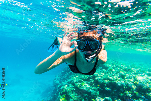 Woman underwater snorkeling with okay sign swimming in sea