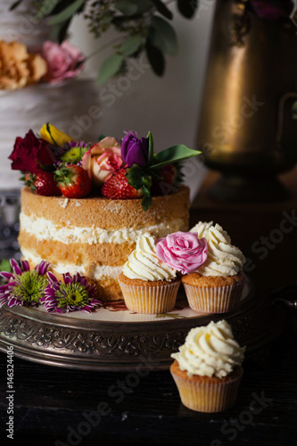 Naked wedding cake and vanilla cupcakes - close up shot of wedding sweet table inspired by Dutch masters still lifes. Dark shadows, window light, grain.