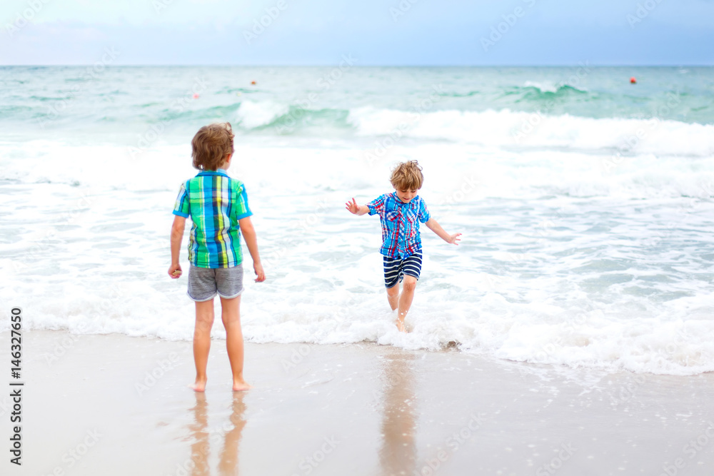 Two kid boys running on tropical beach in Portugal