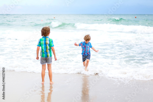 Two kid boys running on tropical beach in Portugal