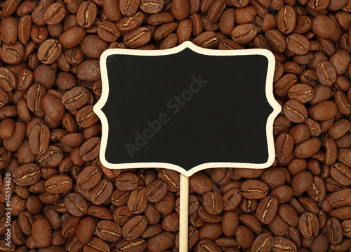 Black chalkboard sign over roasted coffee beans